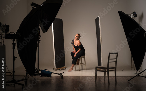Beautiful and attractive model in black dress. Backstage shooting. Fashion, beauty, glamour concept, photo studio with professional lighting equipment, softboxes photo