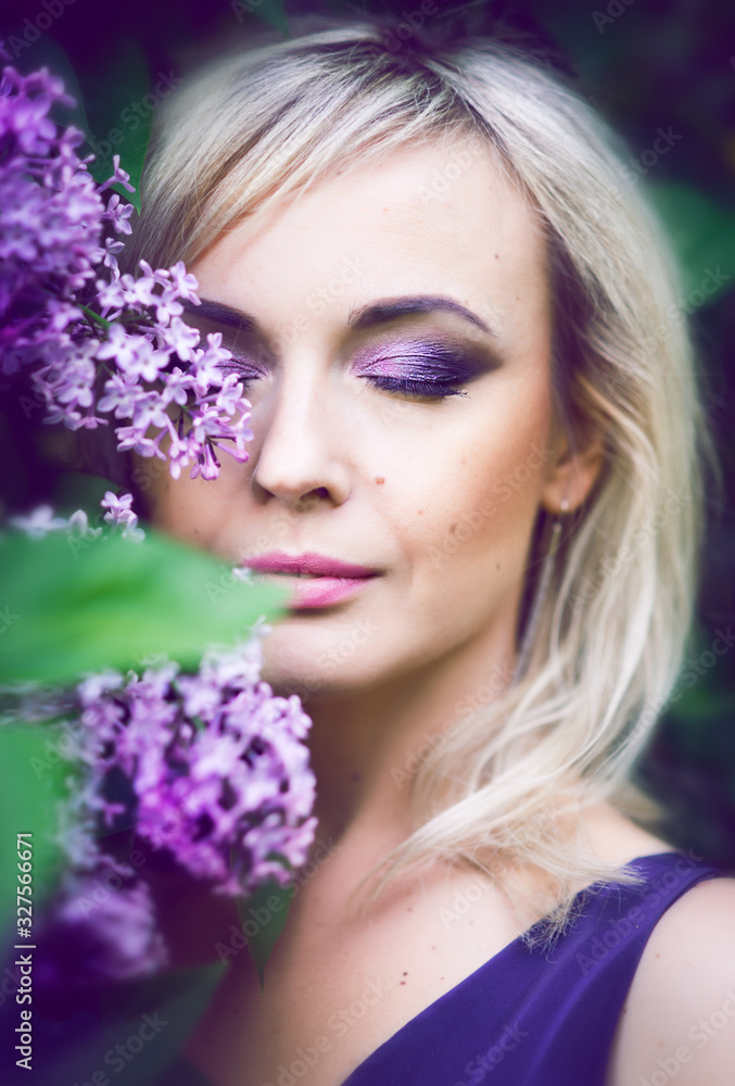 Close-up portrait of a girl with professional makeup in purple on a lilac background in a spring garden. The concept of cosmetics and perfumes Close-up portrait of a girl with professional makeup in purple on a lilac background in a spring garden. The concept of cosmetics and perfumes