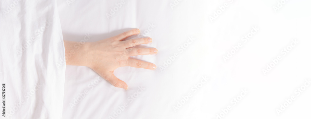 Woman's hand is visible from under the covers as a symbol of fight against insomnia. Tired and exhausted person falls asleep only in the morning. Snow-white bedding. Banner format. Copy space. Woman's hand is visible from under the covers as a symbol of fight against insomnia. Tired and exhausted person falls asleep only in the morning. Snow-white bedding. Banner format. Copy space.