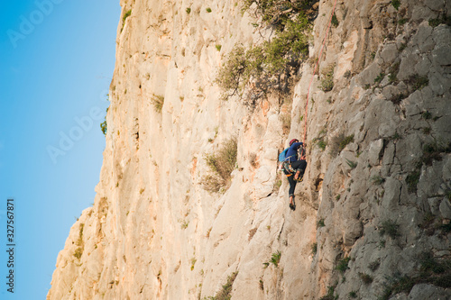 Rock wall climber climbing at sunrise, space to write.