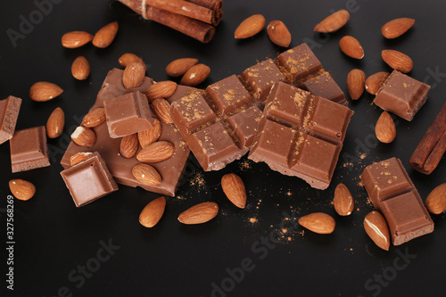 Chocolate with almonds and cinnamon on a dark background close-up