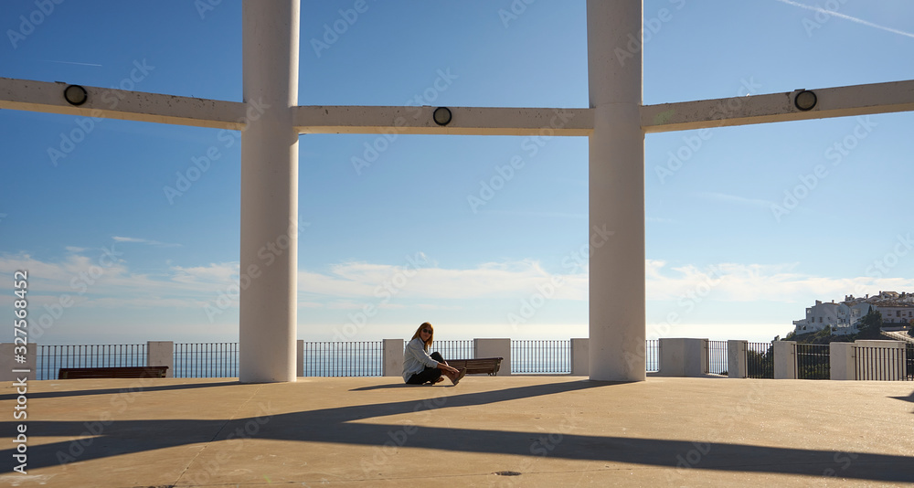 photo shoot blonde woman with columns and the sea in the background