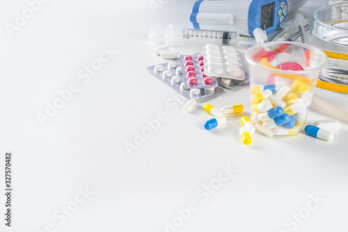 Pharmaceutical medicine pills concept  Assorted various pills  tablets and capsules with medical syringes  thermometer and water glass  copy space mockup  flatlay