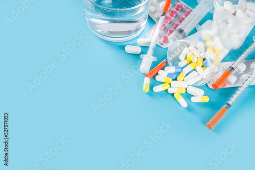 Pharmaceutical medicine pills concept, Assorted various pills, tablets and capsules with medical syringes, thermometer and water glass, copy space mockup, flatlay photo