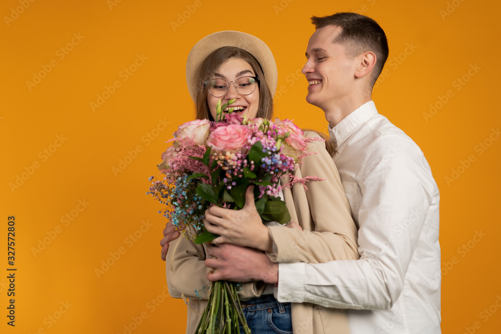 Excited couple with flowers embracing isolated on yellow background Excited couple with flowers embracing isolated on yellow background