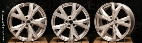 three silvery new cast aluminum wheels on a black background close-up, long layout