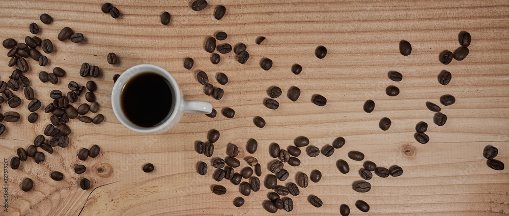 Obraz premium Cup with black coffee on wooden board with beautiful grain and represented coffee beans