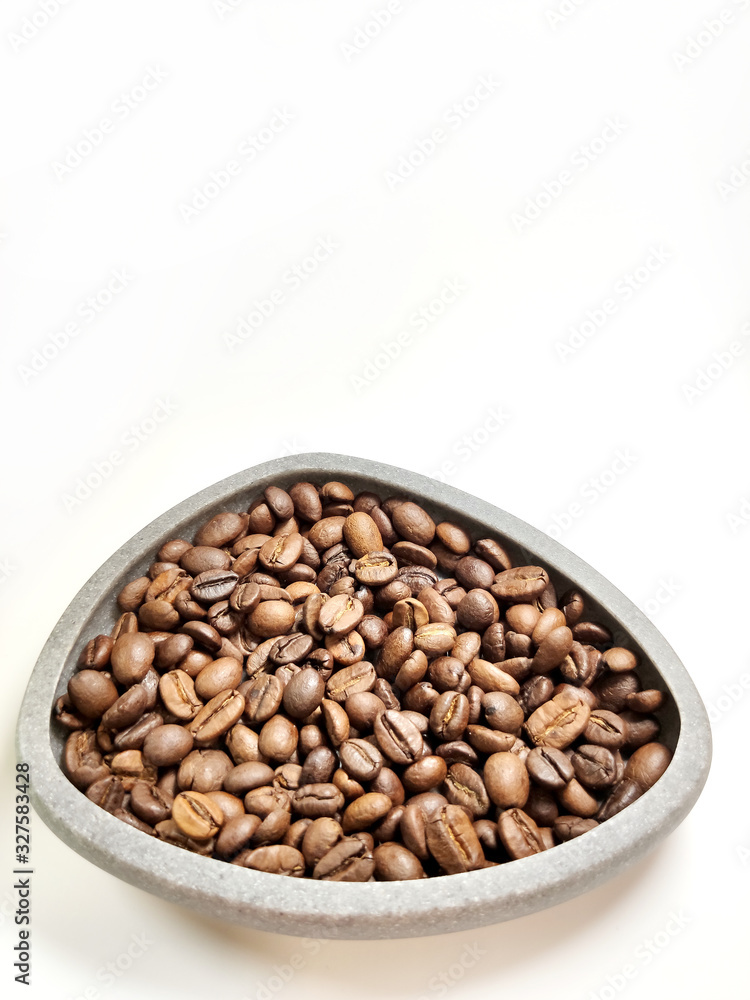 Coffee beans in a gray bowl on a white background.