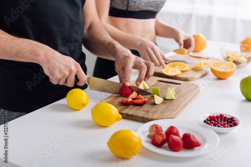 cropped view of man and woman preparing fruit salad