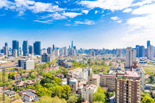 Shanghai, China - Apr 9, 2015: Blue & green Shanghai: Clean, blue sky with clouds and many trees between residential buildings. In the distance the Shanghai Skyline. A different view on the metropolis
