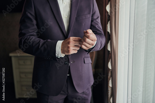 Businessman wears a jacket,male hands closeup,groom getting ready in the morning before wedding ceremony © bondvit