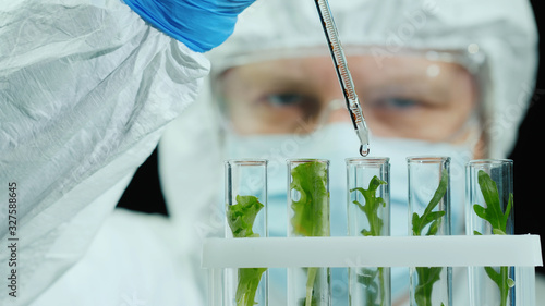 фотографія Scientist in protective jumpsuit and glasses works in the laboratory with sample