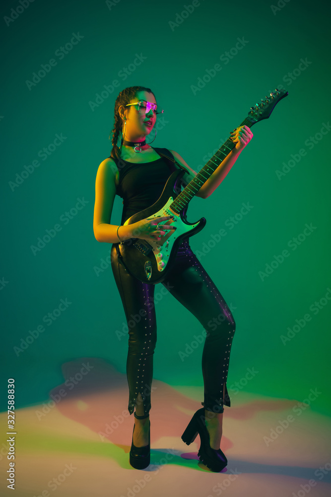 Rockstar. Caucasian female guitarist portrait on green studio ...
