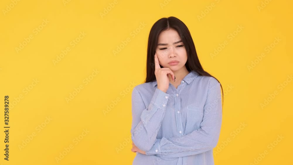 Girl Asian on a yellow background. a thoughtful person and a brilliant idea Girl Asian on a yellow background. a thoughtful person and a brilliant idea