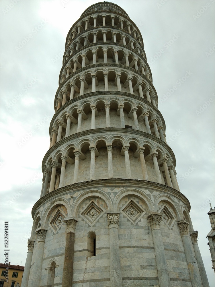 Closeup of the leaning tower of Pisa, looking up at the stone carvings from ground level
