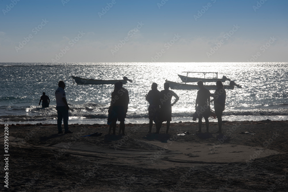 Fototapeta premium a sporty friends group on the beach about to go swimming. Silhouette people group on the beach at Tulum