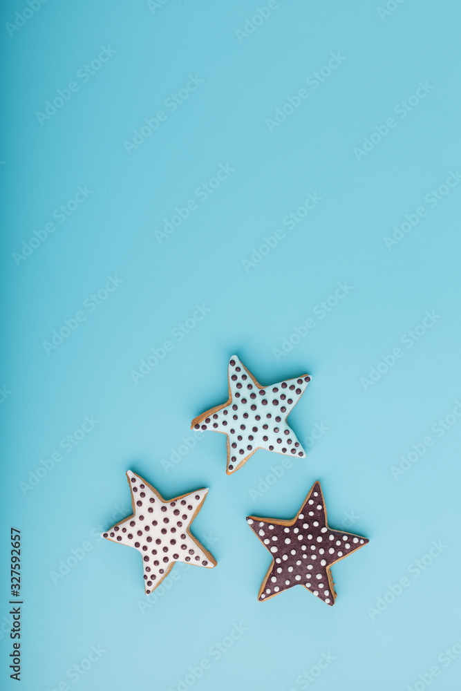 Close-up of three homemade glazed gingerbread cookies made in the form of stars on a blue background. Handmade cookies. Free space. Close-up of three homemade glazed gingerbread cookies made in the form of stars on a blue background. Handmade cookies. Free space.