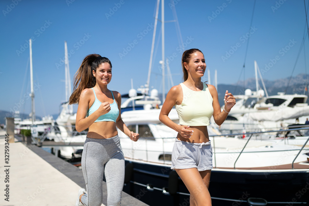 Happy fit people running and jogging together in summer sunny nature