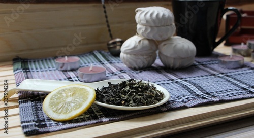 dry green tea, a slice of lemon, marshmallows and items for tea in the cozy kitchen
