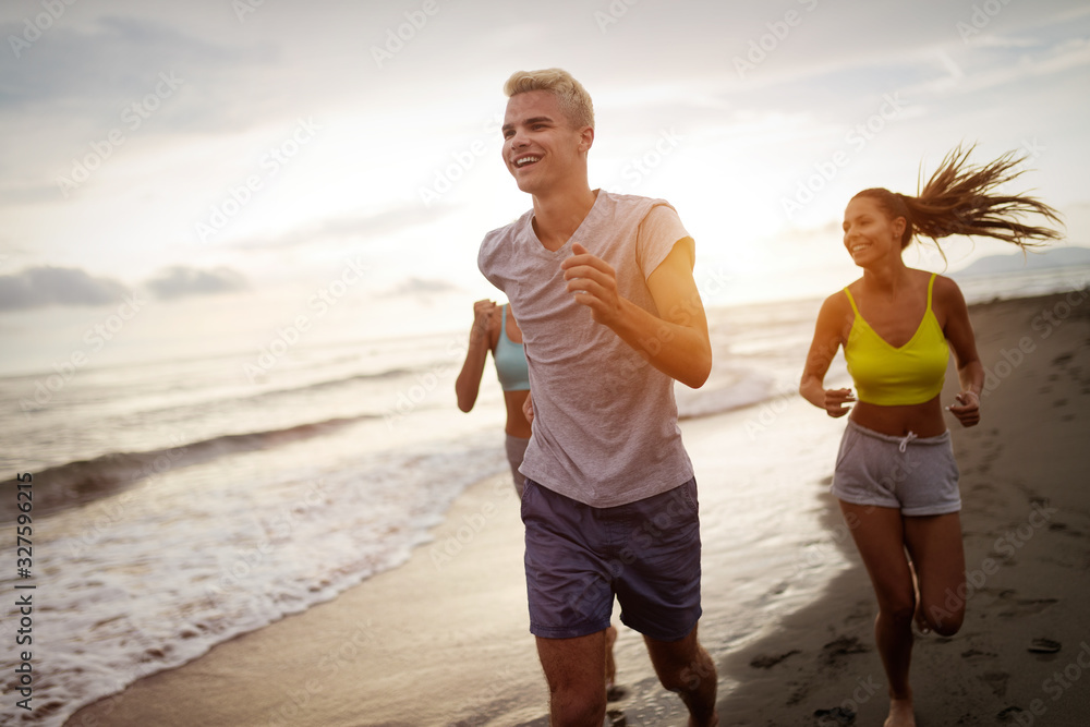 Fototapeta premium Group of friends running at the beach on beautiful summer sunset