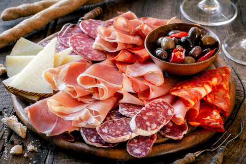 Fototapeta Cures meat platter with cheese and spicy olives served as traditional Spanish tapas on a wooden board