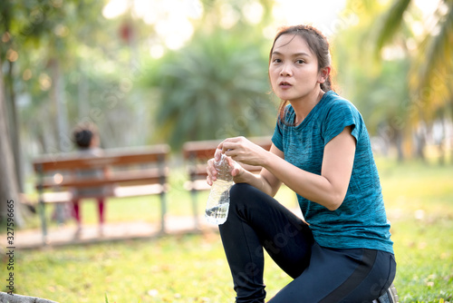 Asian woman drinking water after exercising at the park