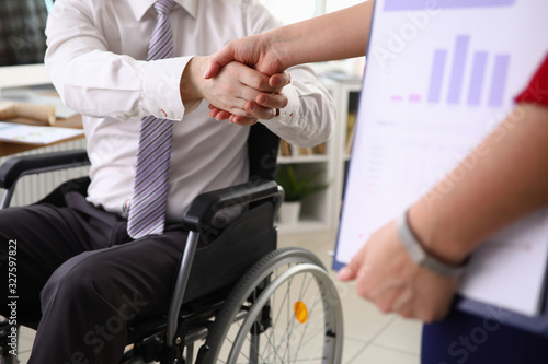 Photos Man in suit sits in wheelchair and shakes his hand