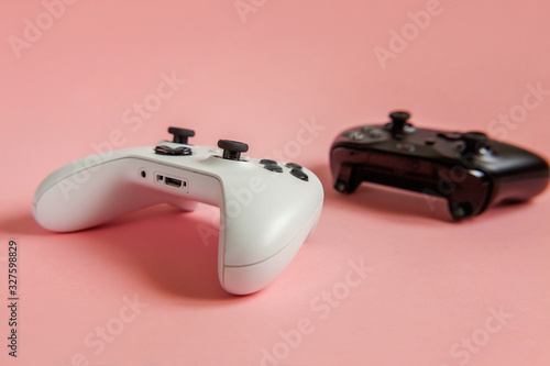 Cyberspace symbol. White and black two joystick gamepad  game console on pastel pink colourful trendy pin-up background. Computer gaming competition videogame control confrontation concept.