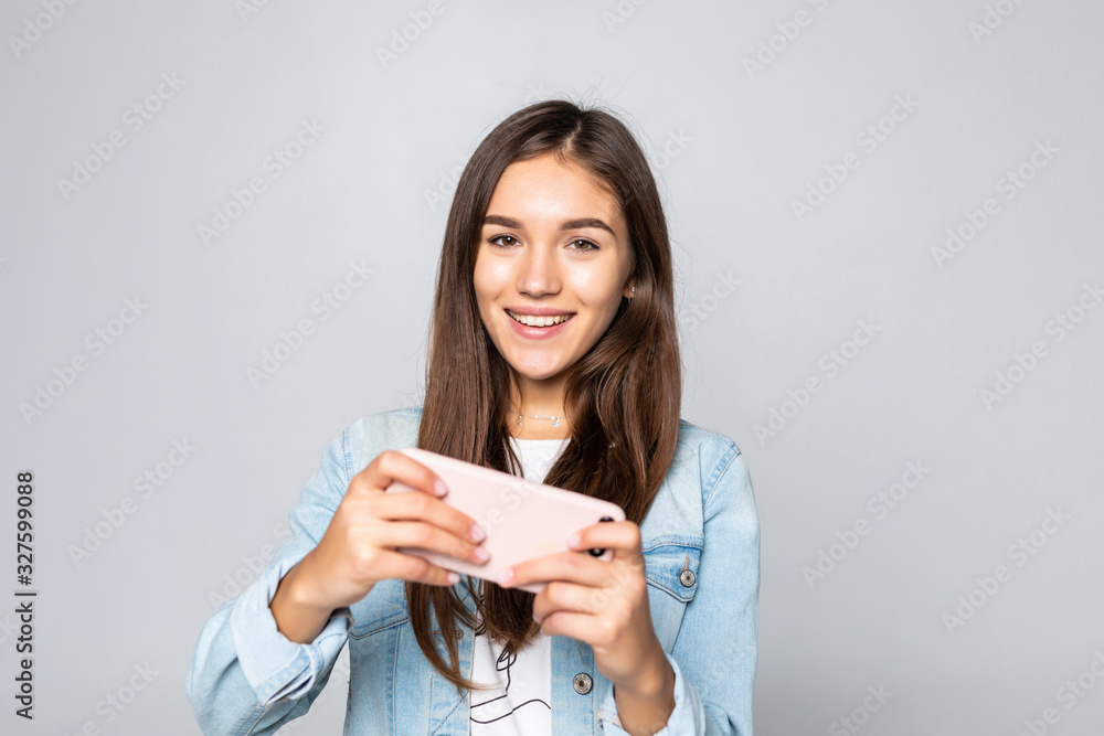 Young woman playing games in her cell phone isolated over a white background Young woman playing games in her cell phone isolated over a white background