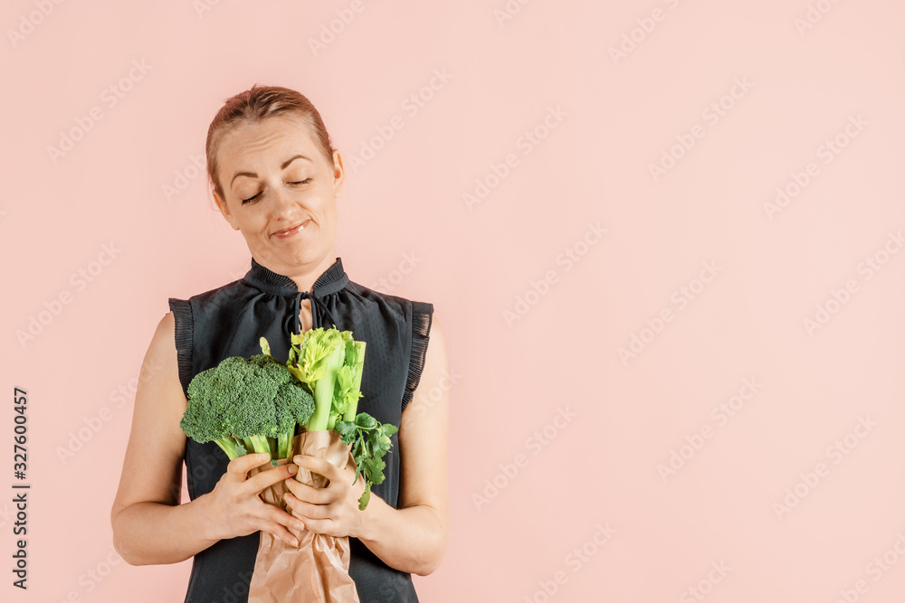 Healthy lifestyle. Girl holds broccoli and green vegetables in her hands, pink background. Diet and proper nutrition. Mock up. Healthy lifestyle. Girl holds broccoli and green vegetables in her hands, pink background. Diet and proper nutrition. Mock up.