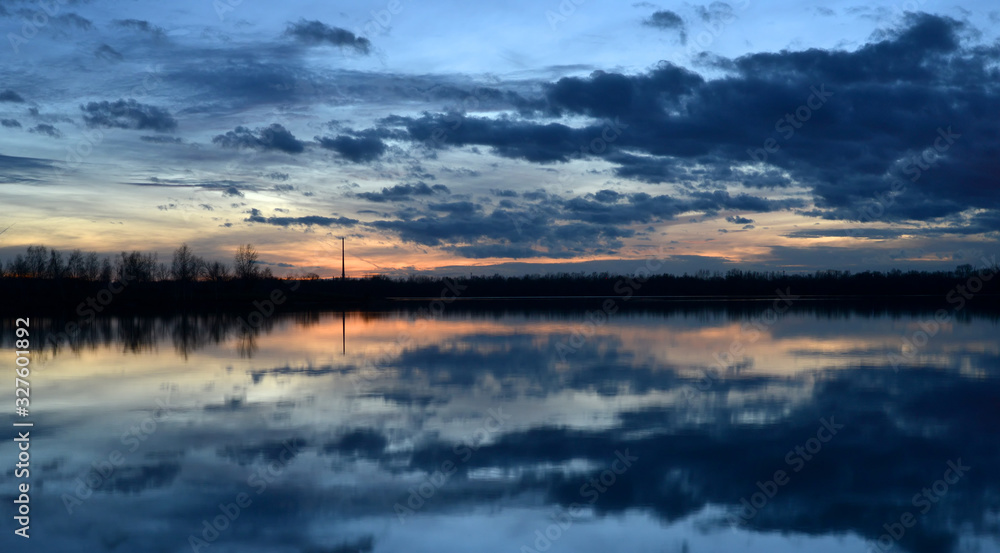 Beautiful evening landscape with reflection of clouds in a lake