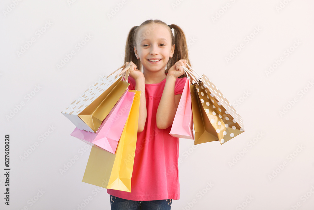Beautiful smiling little girl with bags for shopping on a colored background. The concept of children's shopping. Beautiful smiling little girl with bags for shopping on a colored background. The concept of children's shopping.