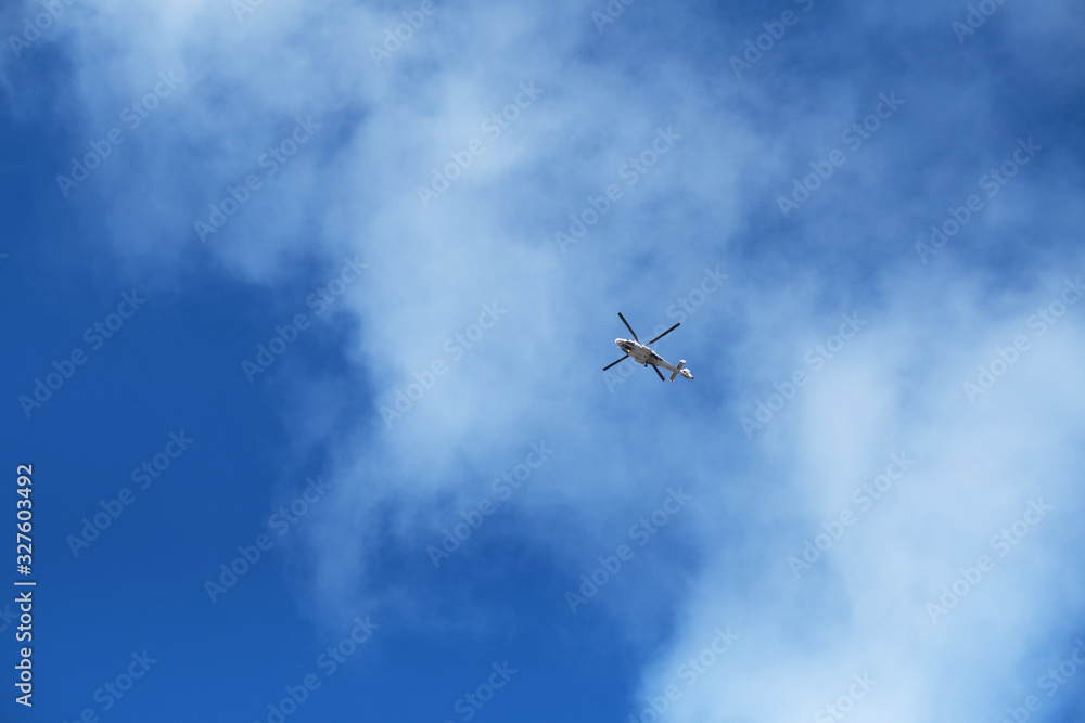 A seaside nautical search and rescue helicopter with rotating blades in the distance with a vivid bright blue sky and clouds. Rescue helicopter and rescue teams are brave. A seaside nautical search and rescue helicopter with rotating blades in the distance with a vivid bright blue sky and clouds. Rescue helicopter and rescue teams are brave.