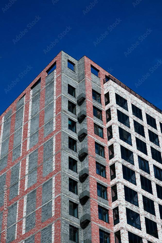 Unfinished apartment building. Construction and real estate. The building is against a blue sky. Unfinished apartment building. Construction and real estate. The building is against a blue sky.
