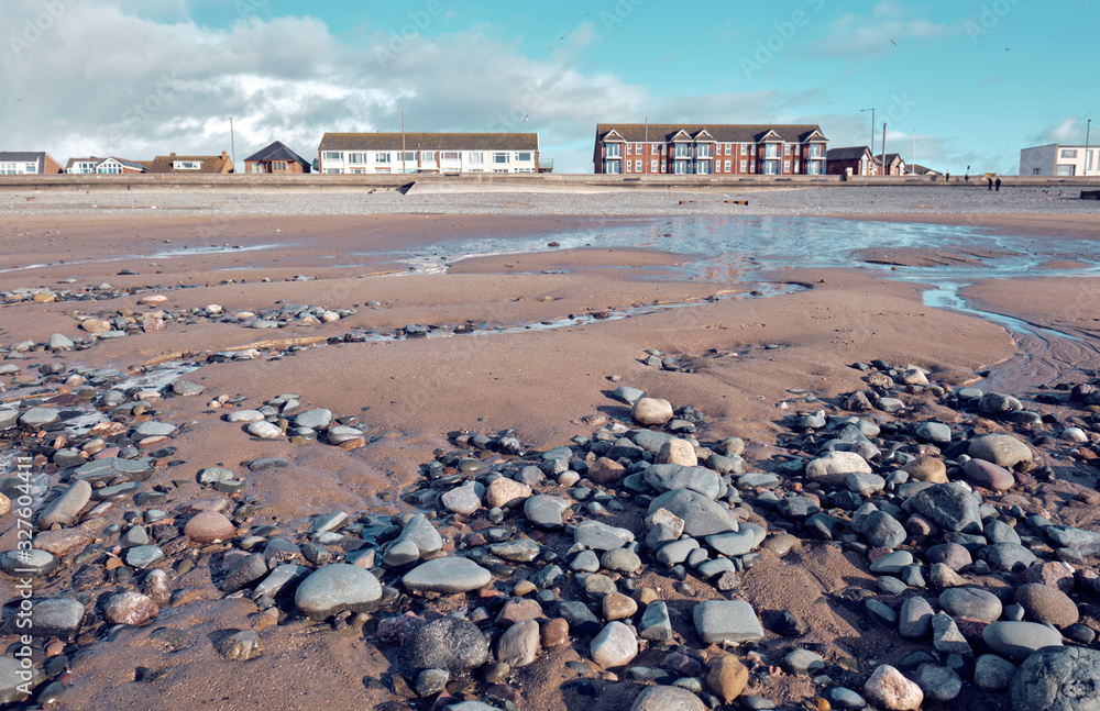 Beautiful sunny winters day on a british beach, with sand ripples, beach stones and the sky reflecting in a water pool. Beautiful sunny winters day on a british beach, with sand ripples, beach stones and the sky reflecting in a water pool.