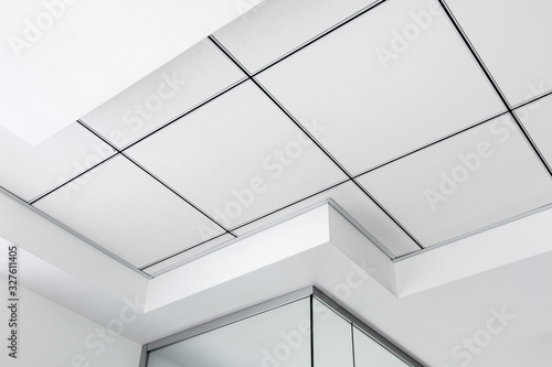 Vászonkép multi-level ceiling with three-dimensional protrusions and a suspended tiled ceiling white color, close up geometric details