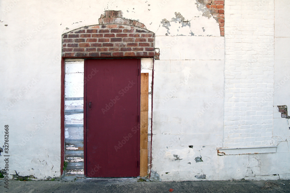 white stucco alley building red door exposed brick