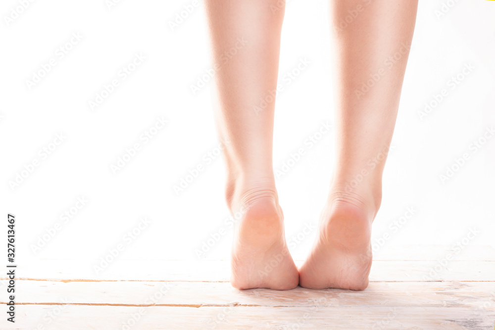 Female, healthy feet, standing on tiptoes on wood floor on a white background.
