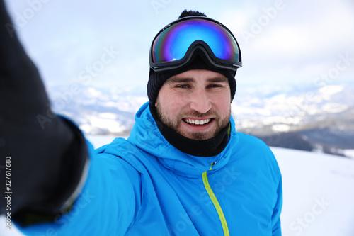 Young man taking selfie at mountain resort. Winter vacation © New Africa
