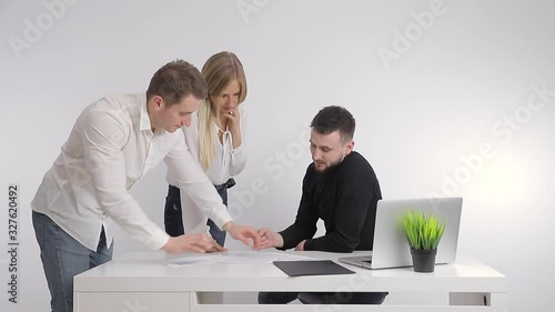 Two businessmen together with the boss in the office discuss the business partnership with the help of papers and look at the comupter together. photo