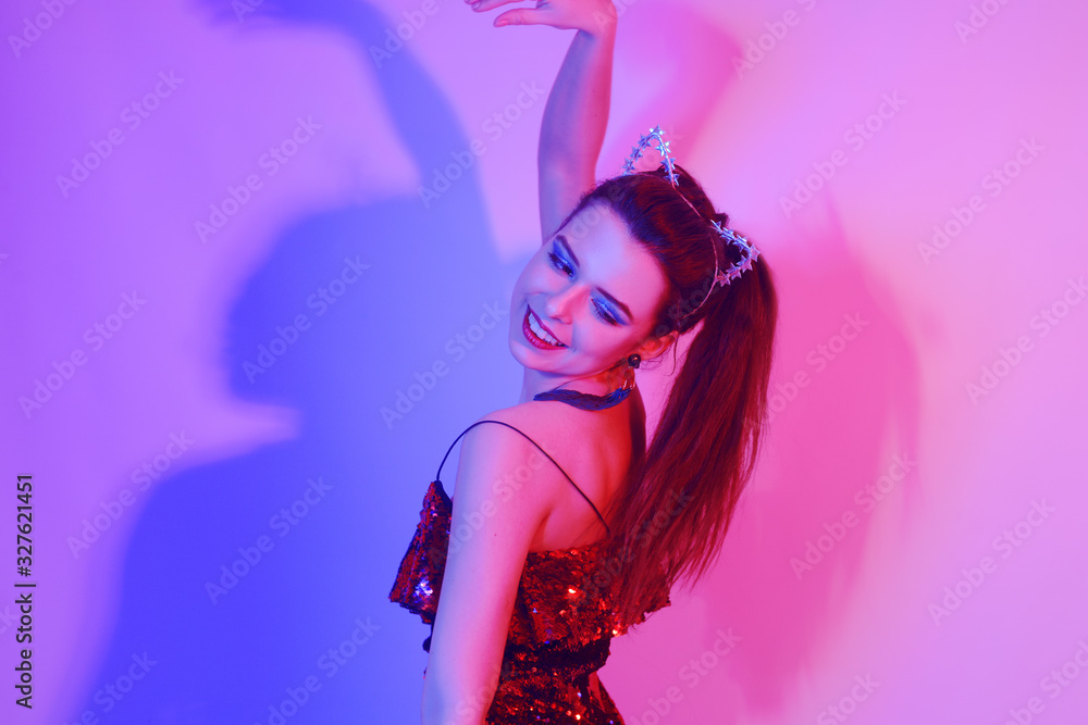 Gorgeous girl dancing in a neon light. A girl in a red shiny dress and with cat ears is dancing Gorgeous girl dancing in a neon light. A girl in a red shiny dress and with cat ears is dancing
