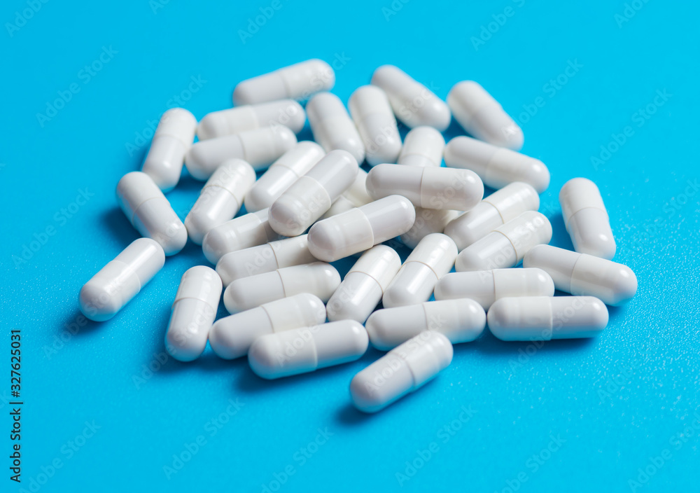 White medicine capsules on blue background White medicine capsules on blue background