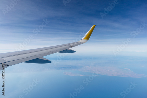 ala de avión de pasajeros airbus a320 sobrevolando el delta del ebro (cataluña, españa), con el cielo zul nublado de fondo.
