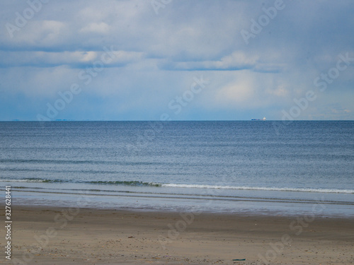 calm beach with shipping vessel in distance, sand