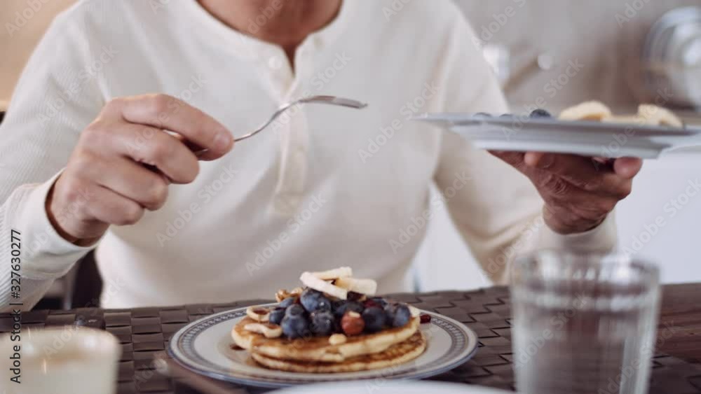 Slow motion shot of mature man preparing pancakes with banana Slow motion shot of mature man preparing pancakes with banana