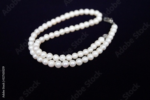 women's decoration necklace is made from freshwater pearls on black background macro photo