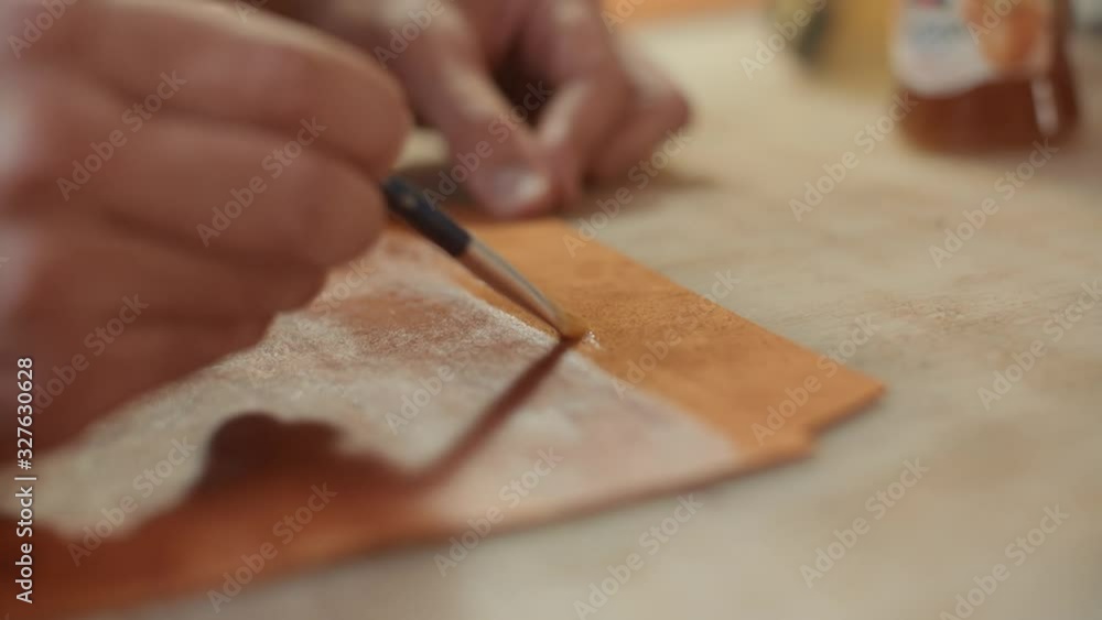 Artisan applies glue to leather with a small brush Artisan applies glue to leather with a small brush