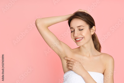 Young woman showing armpit with smooth clean skin on pink background, space for text