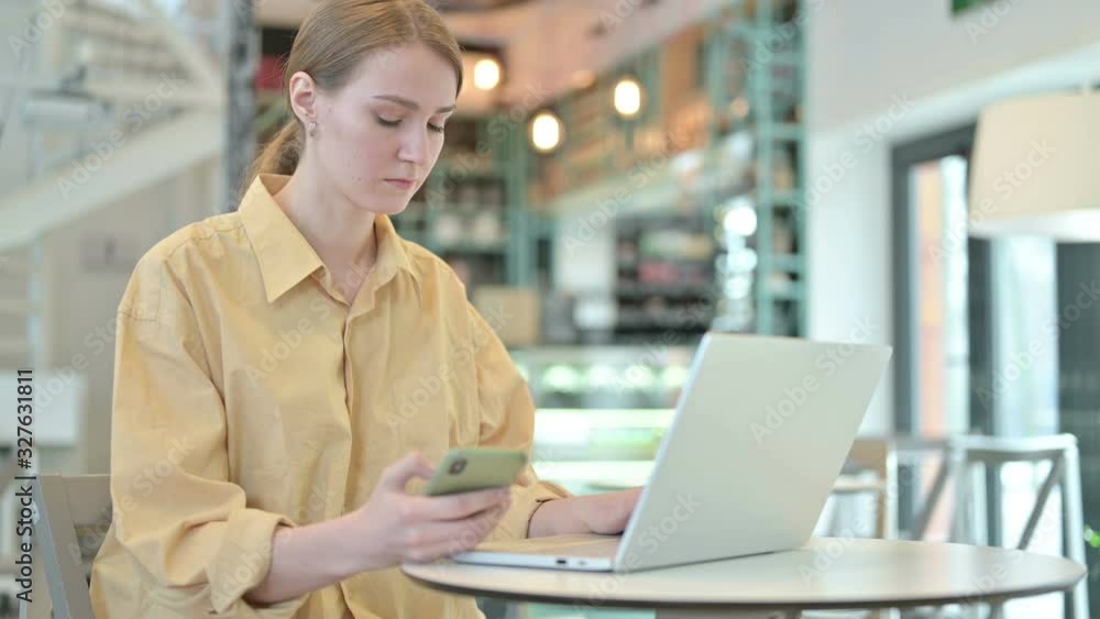 Young Woman using Smartphone and Laptop in Cafe Young Woman using Smartphone and Laptop in Cafe