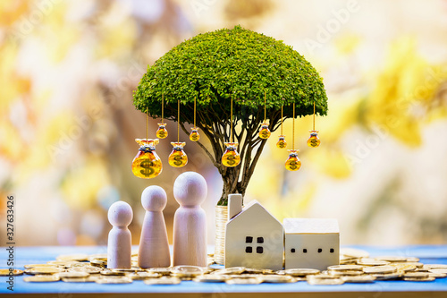 Home model and family put on the stack gold coin with growing as money bag of tree with interest value in the public park, Saving money or loan for business investment of real estate concept.